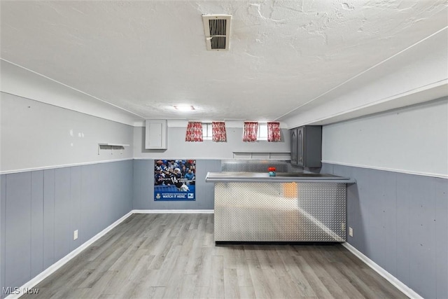 bar featuring a textured ceiling and light wood-type flooring