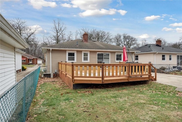 rear view of property with a wooden deck and a lawn