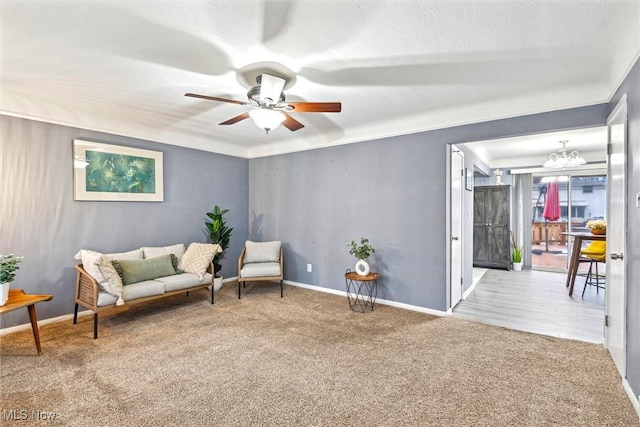 living area featuring ceiling fan with notable chandelier, light colored carpet, and a textured ceiling