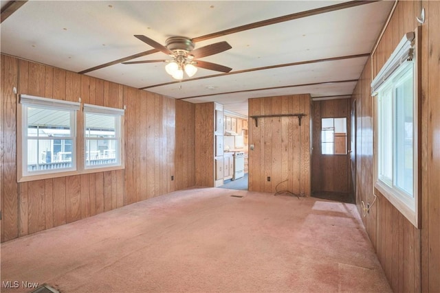 carpeted empty room featuring ceiling fan and wood walls