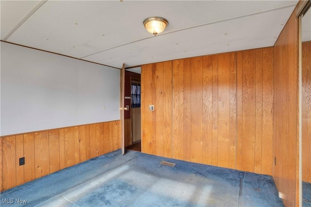 carpeted spare room with wood walls