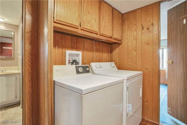 washroom featuring cabinets, wood walls, sink, and washing machine and clothes dryer