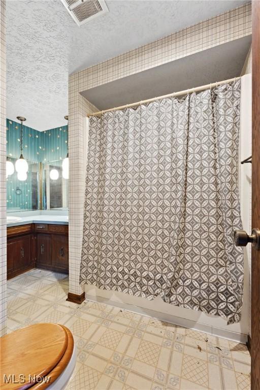 bathroom with vanity, toilet, and a textured ceiling