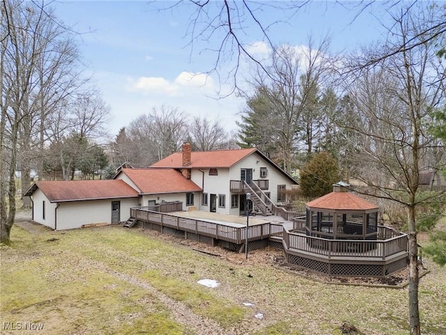 rear view of property with a gazebo, a lawn, and a deck