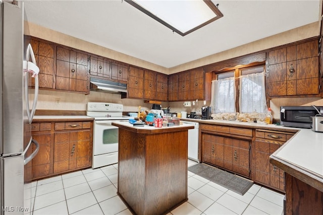 kitchen featuring sink, light tile patterned floors, a center island, and appliances with stainless steel finishes