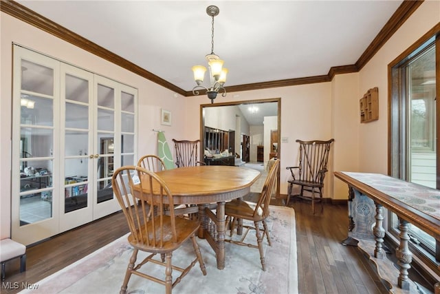 dining area featuring dark wood-type flooring, ornamental molding, an inviting chandelier, and french doors