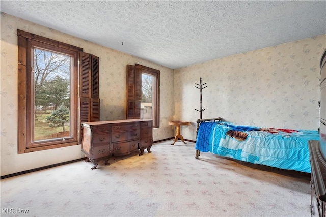 bedroom with multiple windows, light carpet, and a textured ceiling