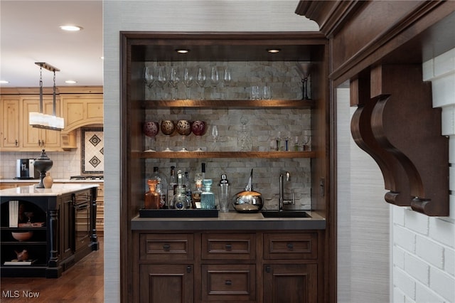 bar featuring tasteful backsplash, sink, dark wood-type flooring, and decorative light fixtures