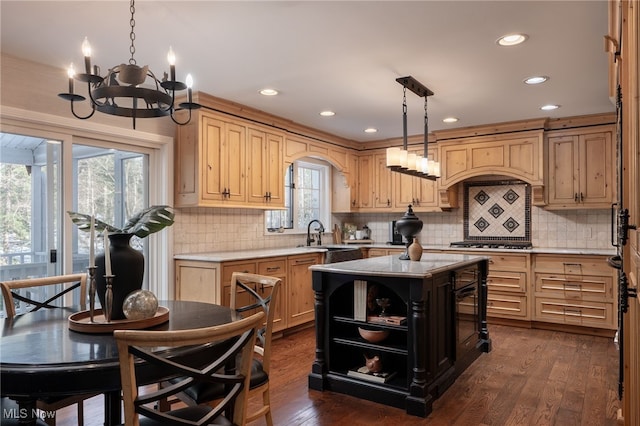 kitchen featuring stainless steel gas cooktop, sink, decorative light fixtures, a center island, and dark hardwood / wood-style floors