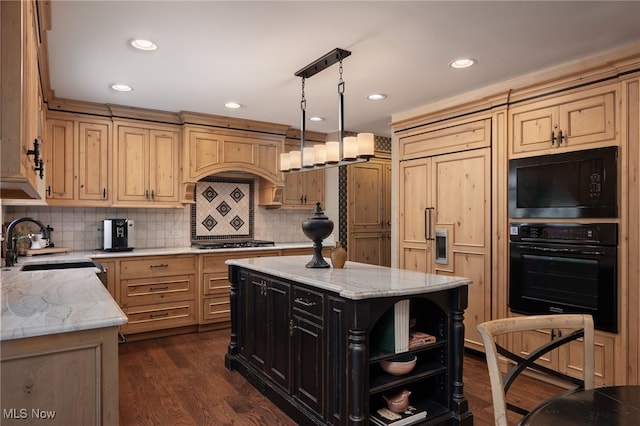 kitchen with light stone counters, a center island, sink, and black appliances