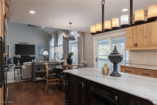 kitchen with lofted ceiling, light stone counters, tasteful backsplash, dark hardwood / wood-style flooring, and decorative light fixtures