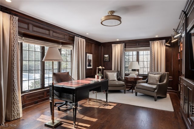 office space featuring hardwood / wood-style floors, wooden walls, ornamental molding, and a healthy amount of sunlight