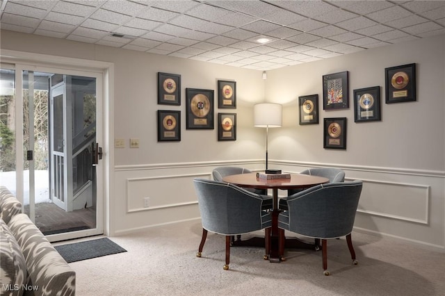 carpeted dining area featuring a drop ceiling