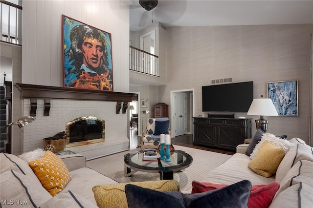 living room featuring ceiling fan, a fireplace, and wood-type flooring