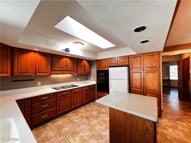 kitchen with a skylight, a kitchen island, and black appliances