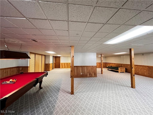 rec room with a paneled ceiling, carpet, and wood walls