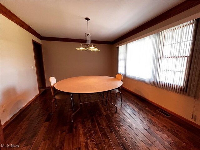 dining room with an inviting chandelier, ornamental molding, and dark hardwood / wood-style floors