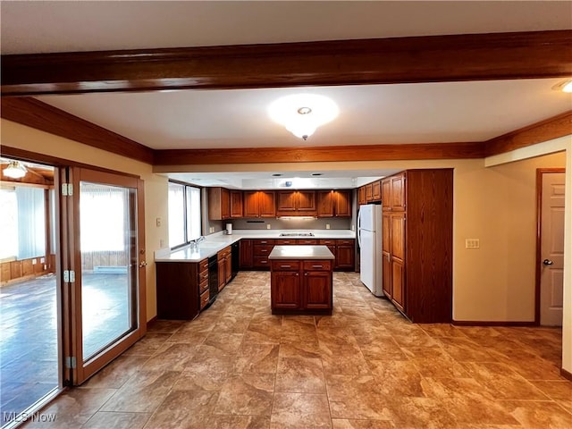 kitchen featuring beamed ceiling, a kitchen island, sink, and white fridge