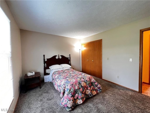 carpeted bedroom with a closet and a textured ceiling