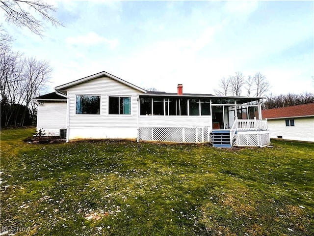 rear view of house featuring a yard and a sunroom