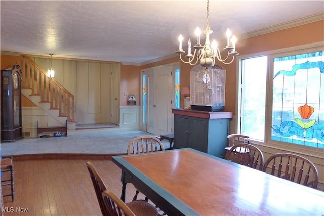 dining area with an inviting chandelier, crown molding, and light hardwood / wood-style flooring