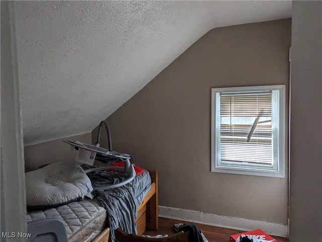 bedroom featuring hardwood / wood-style flooring, lofted ceiling, and a textured ceiling