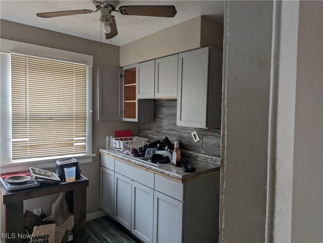 kitchen featuring dark hardwood / wood-style flooring, decorative backsplash, a textured ceiling, and ceiling fan