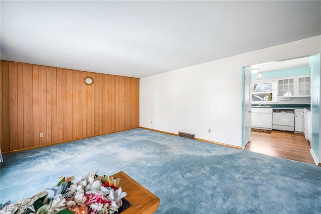 carpeted empty room featuring wooden walls