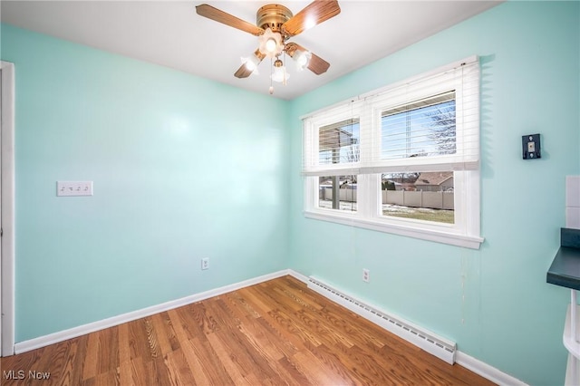 unfurnished room with hardwood / wood-style flooring, ceiling fan, and baseboard heating