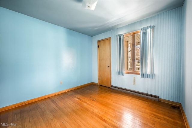 empty room with baseboard heating and light wood-type flooring