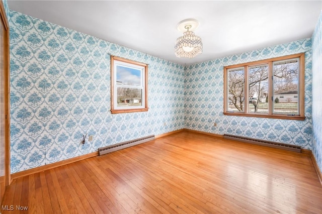 empty room with hardwood / wood-style flooring and a baseboard heating unit