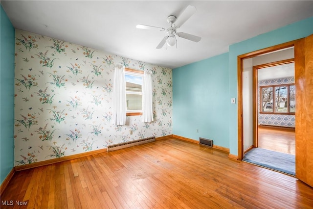 spare room featuring hardwood / wood-style flooring, ceiling fan, and baseboard heating