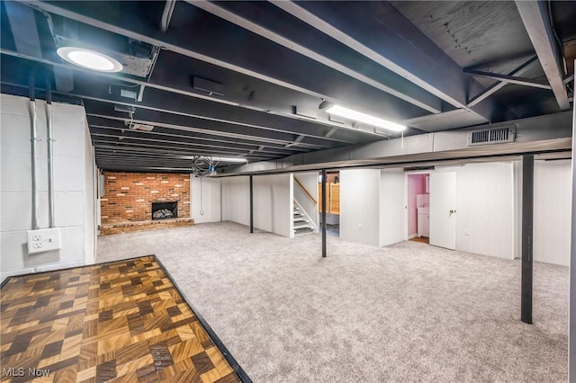 basement with a brick fireplace and carpet flooring