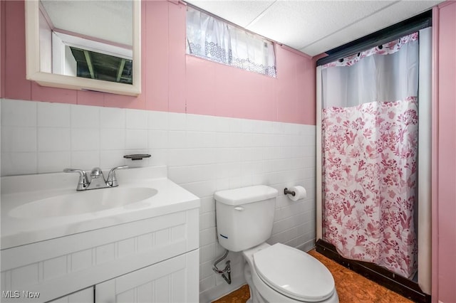 bathroom with vanity, toilet, curtained shower, and tile walls