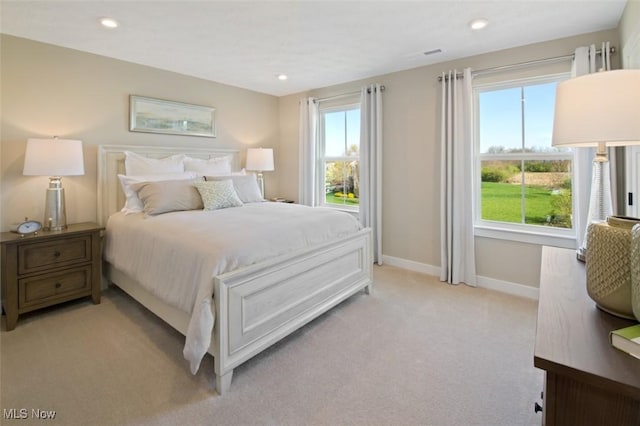 bedroom with light colored carpet and multiple windows