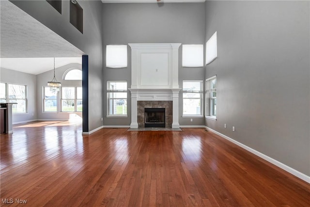 unfurnished living room with a towering ceiling, a fireplace, and hardwood / wood-style floors