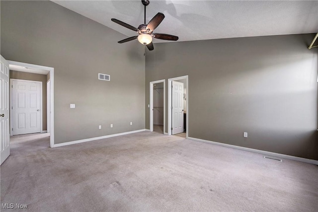 unfurnished bedroom featuring ceiling fan, light colored carpet, a spacious closet, and high vaulted ceiling