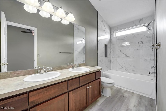 full bathroom featuring tiled shower / bath, wood-type flooring, vanity, ceiling fan, and toilet