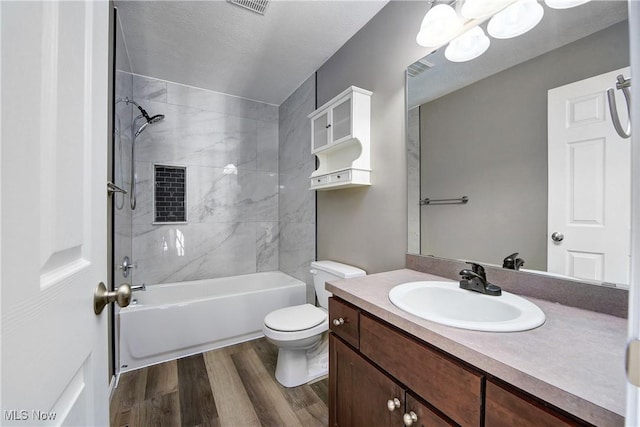 full bathroom with vanity, hardwood / wood-style floors, tiled shower / bath, and toilet