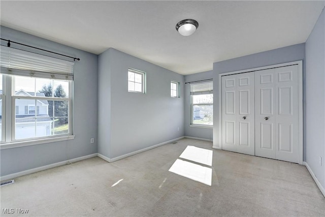 unfurnished bedroom with light colored carpet and a closet