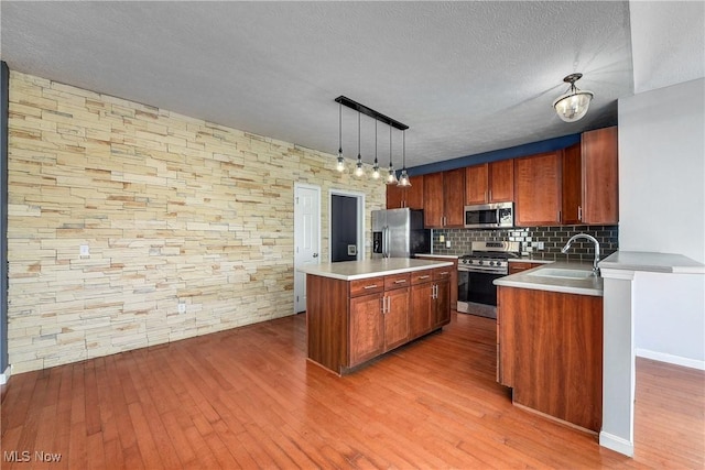 kitchen featuring sink, hanging light fixtures, hardwood / wood-style floors, stainless steel appliances, and a kitchen island