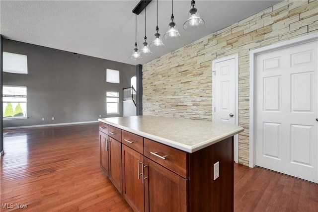 kitchen with hanging light fixtures, dark hardwood / wood-style floors, a textured ceiling, and a center island