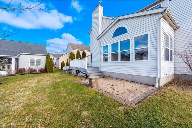 back of property featuring a patio area, a lawn, and a deck