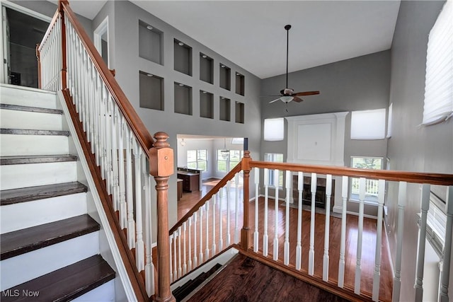 stairway with hardwood / wood-style floors, ceiling fan, and a high ceiling