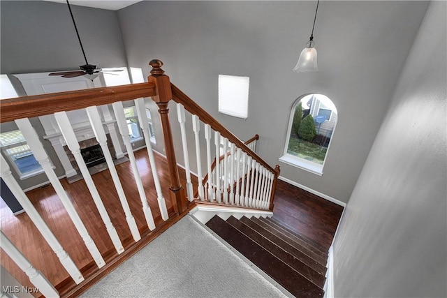 staircase featuring ceiling fan, hardwood / wood-style floors, and a towering ceiling