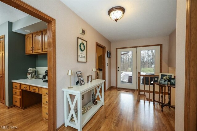 doorway to outside featuring french doors, built in desk, and light hardwood / wood-style floors