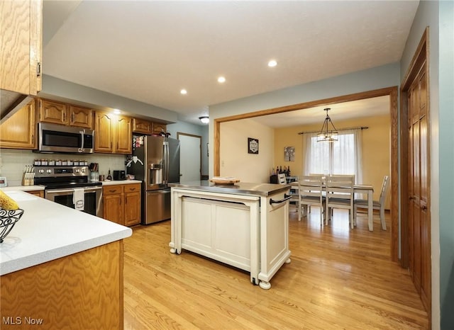 kitchen with pendant lighting, light hardwood / wood-style flooring, appliances with stainless steel finishes, an inviting chandelier, and decorative backsplash