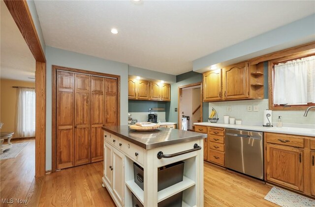 kitchen with a kitchen island, decorative backsplash, stainless steel counters, stainless steel dishwasher, and light hardwood / wood-style floors