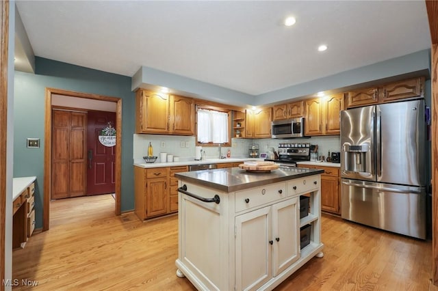 kitchen featuring tasteful backsplash, light wood-type flooring, a center island, and appliances with stainless steel finishes