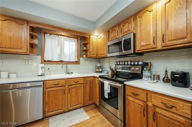 kitchen featuring stainless steel appliances, sink, light wood-type flooring, and decorative backsplash